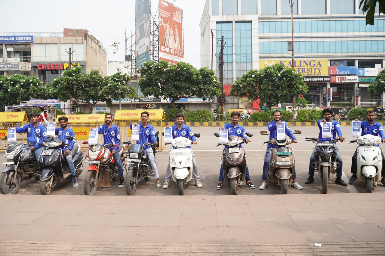 Docatho riders in blue uniforms on bikes, holding flyers on a Raipur street
