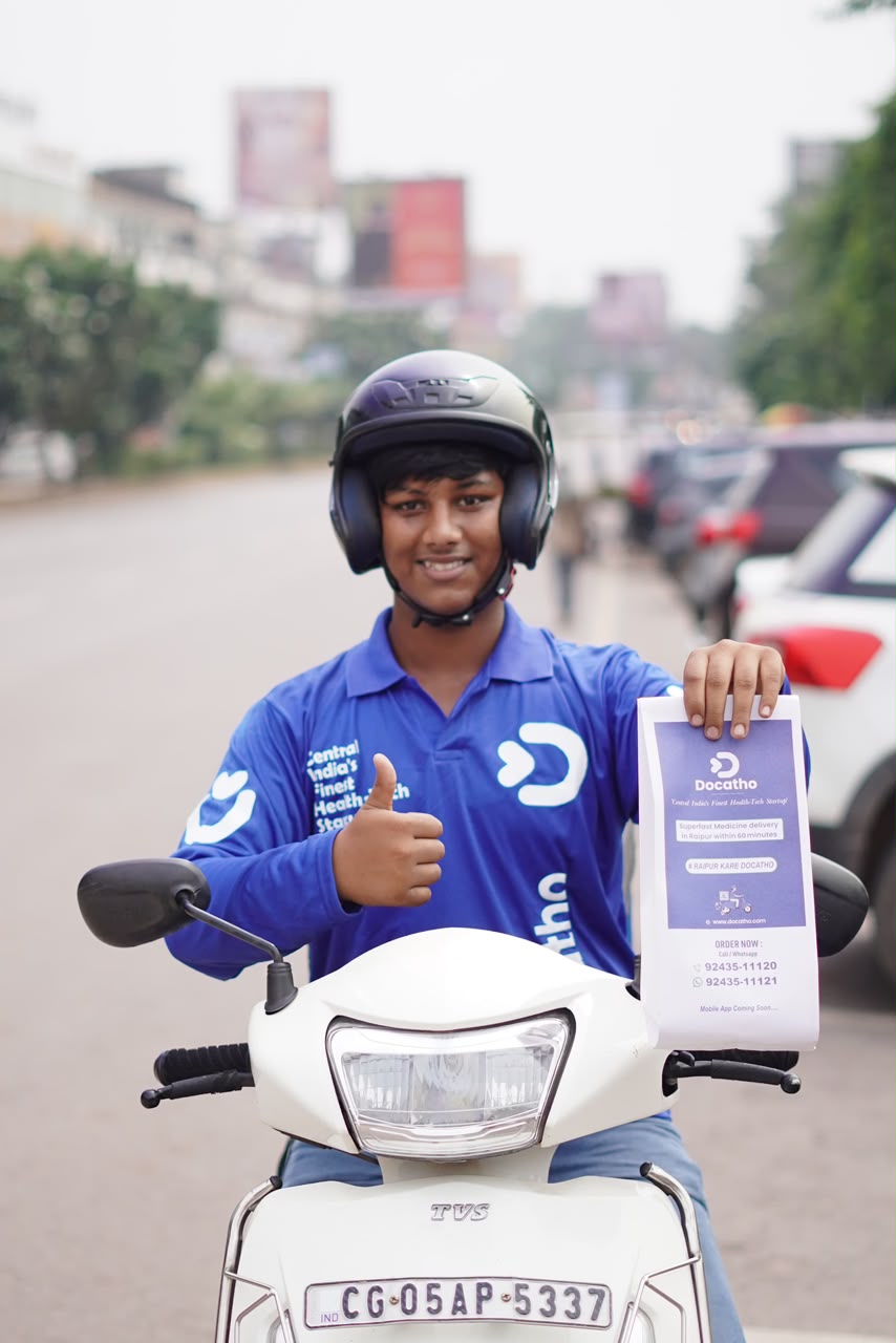 A helmeted Docatho rider on a scooter, holding a 60-minute medicine delivery flyer