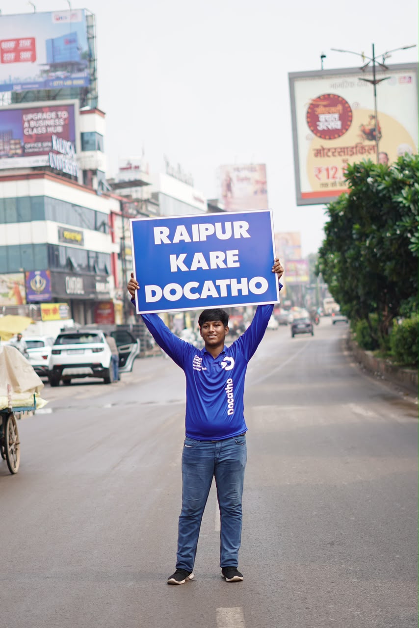 A Docatho rider holding a Raipur Kare Docatho board in the middle of a Raipur street